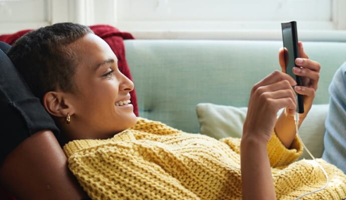 femme sur un canapé regardant un téléphone portable lançant Norton 360 avec AntiVirus Plus.