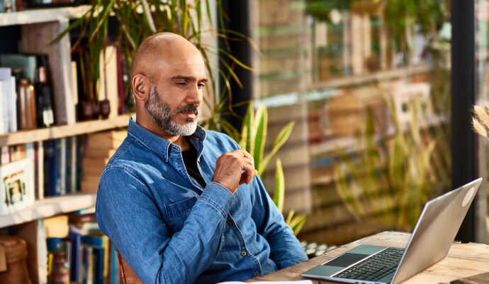 Homme assis à un bureau regardant un ordinateur portable