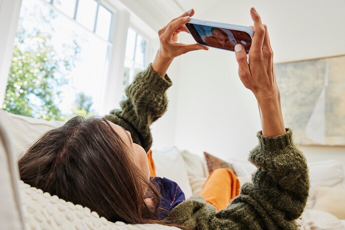 Femme couchée regardant un téléphone portable